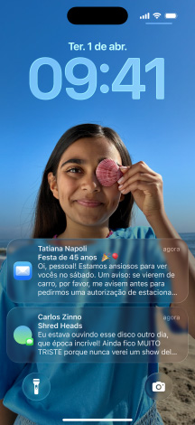 iPhone, cinco modelos, cada um se sobrepondo levemente ao seguinte, os modelos mostram da esquerda para a direita: uma conversa com um plano de fundo no Mensagens; a Tela de Início com ícones de app coloridos; a Tela Bloqueada com uma foto, os números das horas em Liquid Glass e duas notificações na parte inferior da tela; os ícones de app transparentes em Liquid Glass; o reprodutor de música em Liquid Glass.