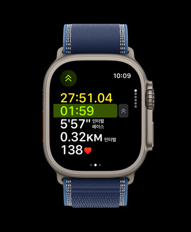 첨단 실외 달리기 운동 수치가 보이는 내추럴 색상 티타늄 케이스의 Apple Watch Ultra 3, 그리고 블루/브라이트 블루 색상 트레일 루프