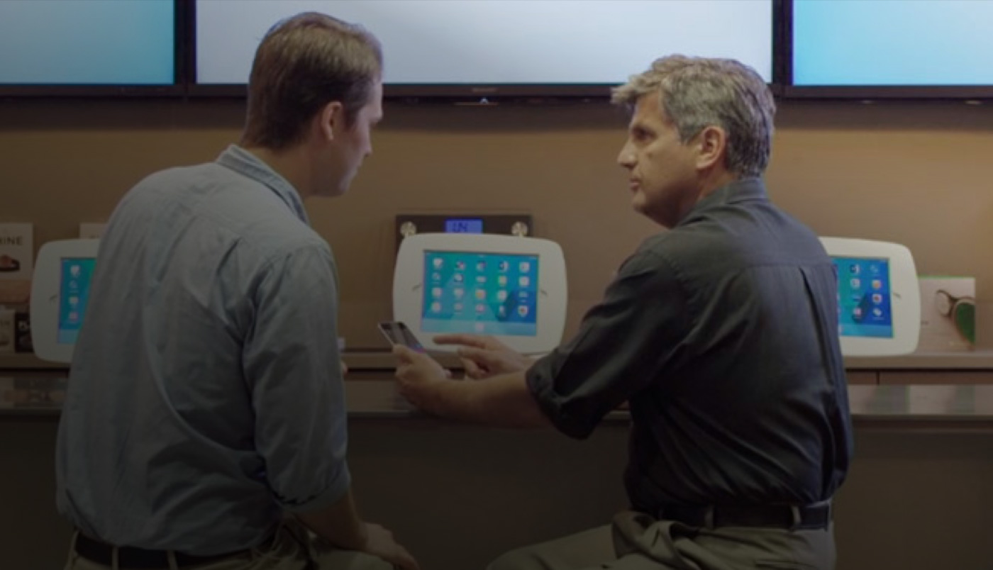 Dos hombres sentados en el O Bar miran la pantalla de un iPhone.