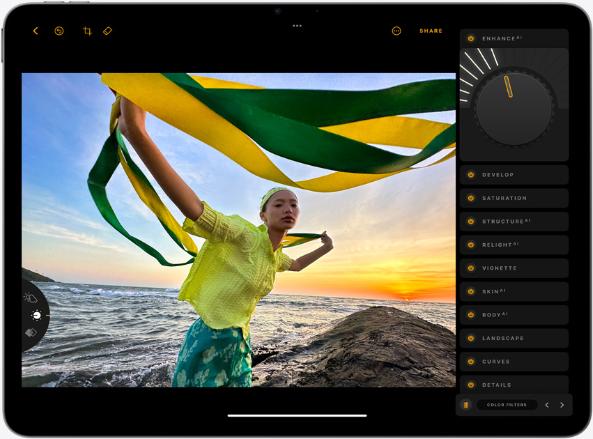 iPad Air, landscape orientation, screen displays a photograph of a girl holding yellow and green strands, standing in front of a sunset over the ocean